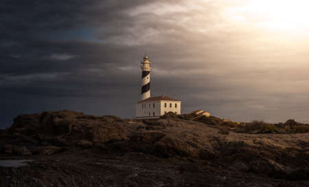 Misty lighthouse in the night with cloudy skyの写真素材
