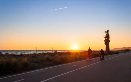 A couple of mountain bikers in sunset next to the beachの写真素材