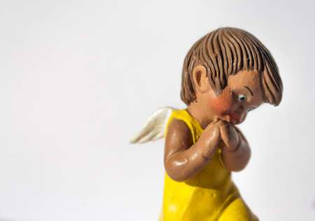 Cute angel figurine with yellow dress and white wings in a religious sceneの写真素材