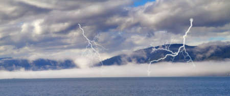 A photo of a sea, fog, mountains and thunderの写真素材