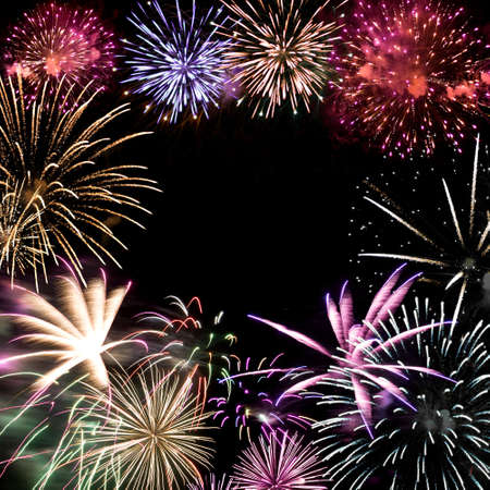 Beautiful fireworks exploding over a dark night sky with copy space in the center.