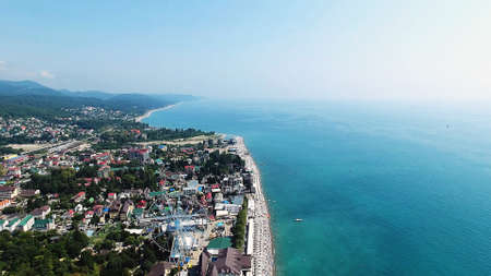 Beach on the sea with tourists resting on the background of the city and water. Beautiful sunny day.の写真素材