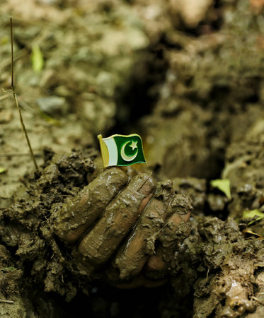 The hand of a child with a green flag in the mud.の写真素材
