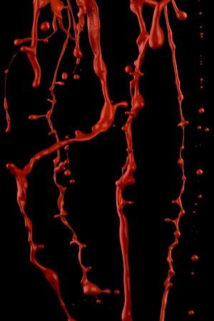 Splashes of red paint. Isolated paint on black in a movement.の写真素材