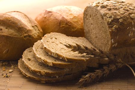 Fresh bread with ear of wheat. Still life view of freshly baked bread with part broken off, and ear...