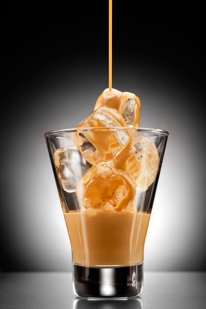 Irish spirit! Irish creme liqueur pouring into a glass full of ice.の写真素材