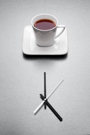 When the day is done the very teatime come - A white mug filled with tea over minimalistic clock の写真素材
