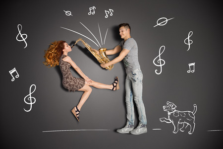 Happy valentines love story concept of a romantic couple against chalk drawings background  Female playing the sax for her boyfriend の写真素材