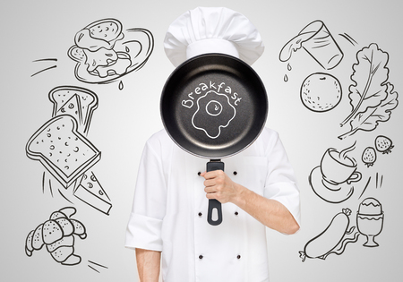 Restaurant chef hiding behind a frying pan with sketchy fried eggs for breakfast menu.の写真素材