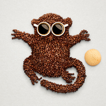 A funny tarsier made of roasted coffee beans, two cups and star anise with an oatmeal cookie.の写真素材