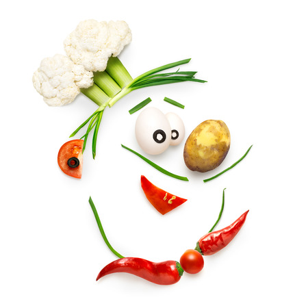 Creative food concept of a funny cartoon chef face made of vegetables isolated on white.の写真素材