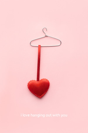 Creative valentines concept photo of a heart on a hanger on pink background.の写真素材