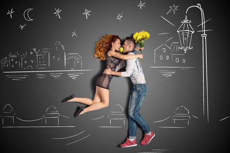 Happy valentines love story concept of a romantic couple having a date under the lantern on the quay against chalk drawings background.の写真素材