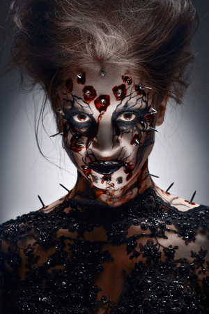 A creepy halloween makeup of a witch with a bloody peircing and cracked face paint.の写真素材