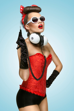 The pin-up photo of a cute girl in sunglasses with unplugged music headphones.の写真素材