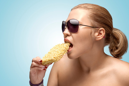 A creative portrait of a beautiful hungry woman eating a block of instant noodles.の写真素材