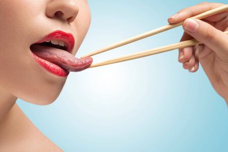 The photo of girl lower face with eating sticks hoding tongue.の写真素材