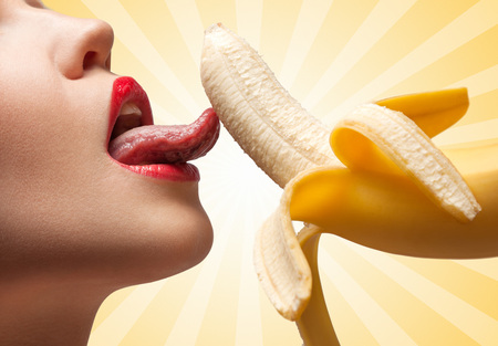 A face of a hot girl that is licking a half-peeled yellow banana on colorful abstract cartoon style background.の写真素材