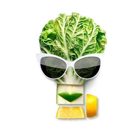Quirky food concept of cubist style female face in sunglasses made of fruits and vegetables, isolated on white.の写真素材