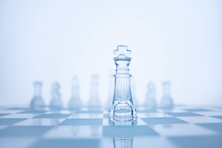 Photo of chess king standing in front of the same colour set in bright background.の写真素材