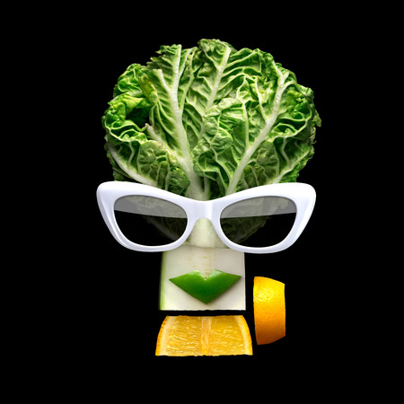 Quirky food concept of cubist style female face in sunglasses made of fresh fruits on black background.の写真素材