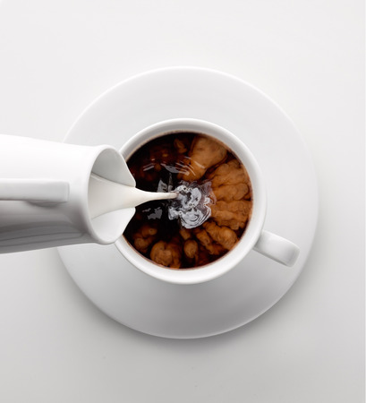 Adding milk to a cup of coffee.の写真素材