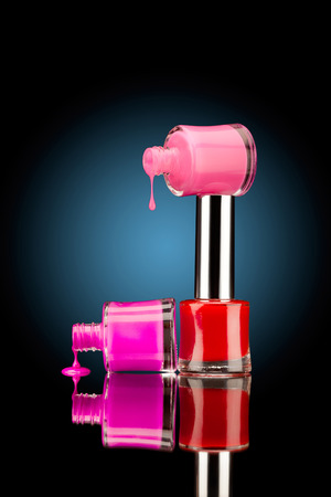 Three nail polish bottles of bright colors with juicy falling drops against black background.の写真素材