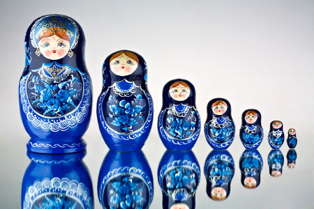 A set of seven blue painted Russian nesting dolls on mirror surface.の写真素材