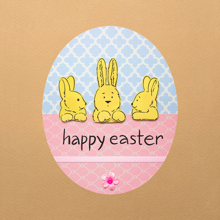 Creative easter concept photo of three rabbits in a colorful egg made of paper on brown background.の写真素材