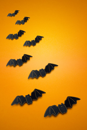 Creative halloween concept photo of bats made of paper on orange background.の写真素材