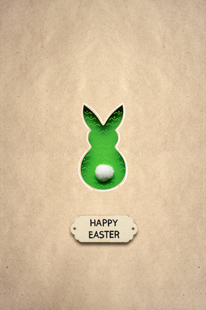 Creative easter concept photo of a rabbit made of paper on brown background.の写真素材