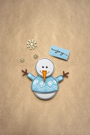 Creative photo of a snowman made of paper on brown background.の写真素材