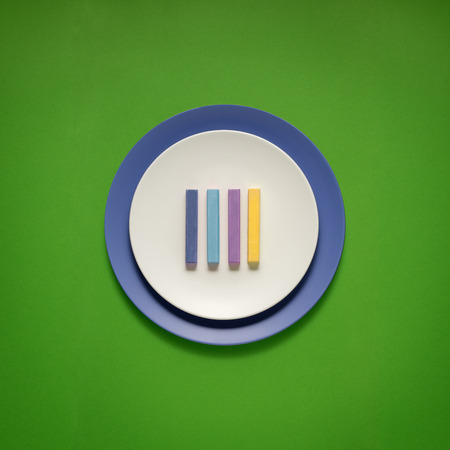 Creative concept photo of kitchenware, painted plate with food on it on green background.の写真素材