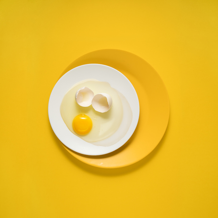 Creative concept photo of kitchenware, painted plate with food on it on yellow background.の写真素材