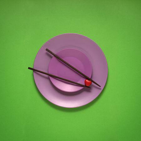 Creative concept photo of kitchenware, painted plate with food on it on green background.の写真素材