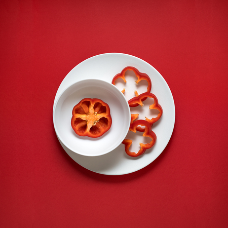 Creative concept photo of kitchenware, painted plate with food on it on red background.