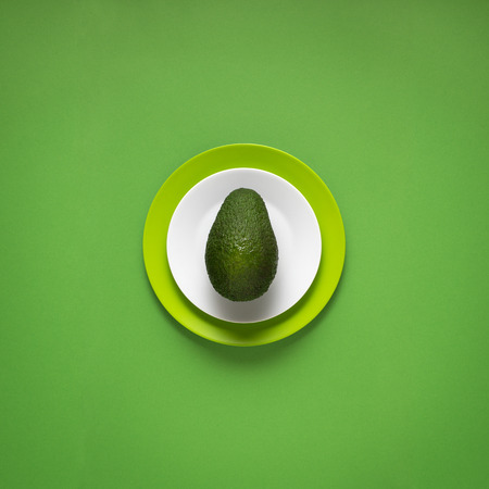 Creative concept photo of kitchenware, painted plate with food on it on green background.