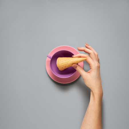 Creative concept photo of kitchenware with hand, painted plate with food on it on grey background.の写真素材