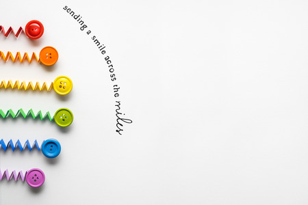 Creative concept photo of a rainbow  made of paper and buttons on grey background.の写真素材