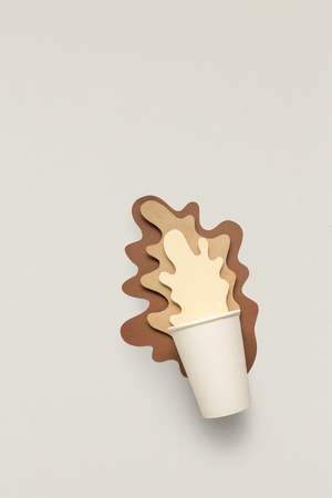 Creative concept photo of take away cup with splashing coffee made of paper on grey background.の写真素材