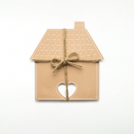 Creative concept photo of a house with a bow made of paper on white background.の写真素材