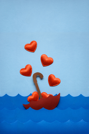 Creative valentines concept photo of umbrella with hearts floating in the sea on blue background.の写真素材