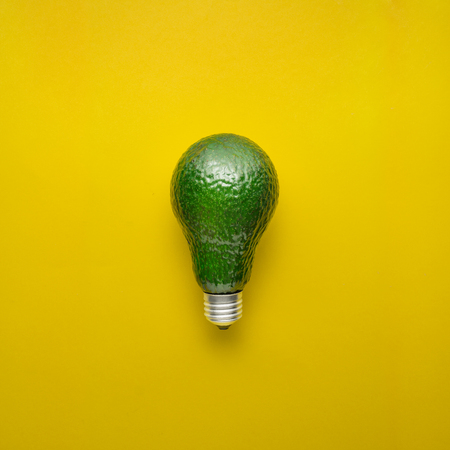 Creative concept photo of avocado as electric bulb on yellow background.の写真素材