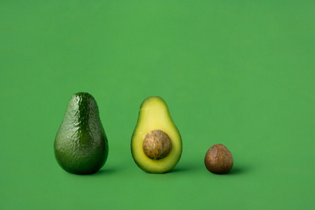 Creative concept photo of avocados on green background.の写真素材