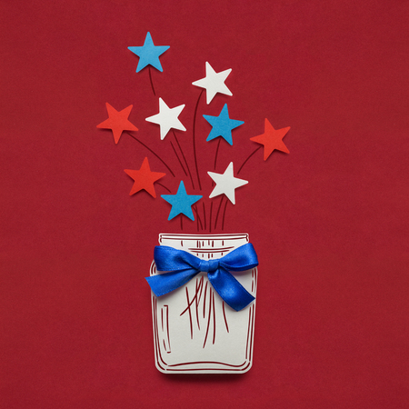 Creative 4th of July concept photo of stars in a bottle made of paper on red background.の写真素材