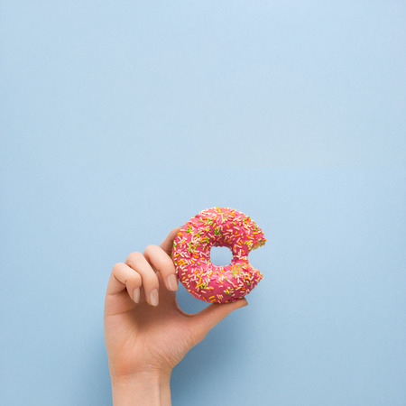 Creative concept photo of  hand holding donut on blue background.の写真素材