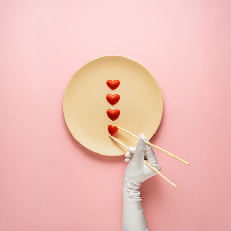Creative concept photo of kitchenware with hand, painted plate with food on it on pink background.の写真素材