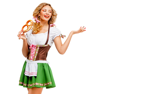 Creative concept photo of Oktoberfest waitress wearing a traditional Bavarian costume with pretzels isolated on white background.の写真素材