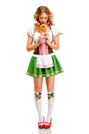 Creative concept photo of Oktoberfest waitress wearing a traditional Bavarian costume with pretzels isolated on white background.の写真素材