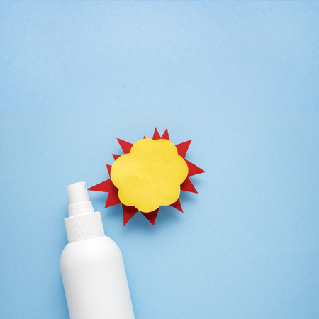 Creative concept photo of cosmetic bottle with splashing liquids made of paper on blue background.の写真素材